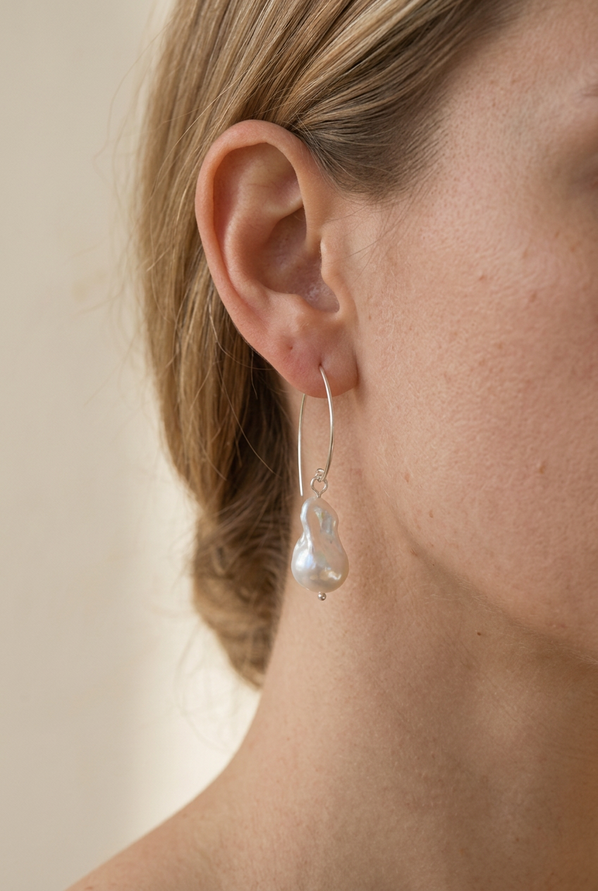AI-generated visualization of a Greta pearl earring worn on an ear; scale is illustrative.